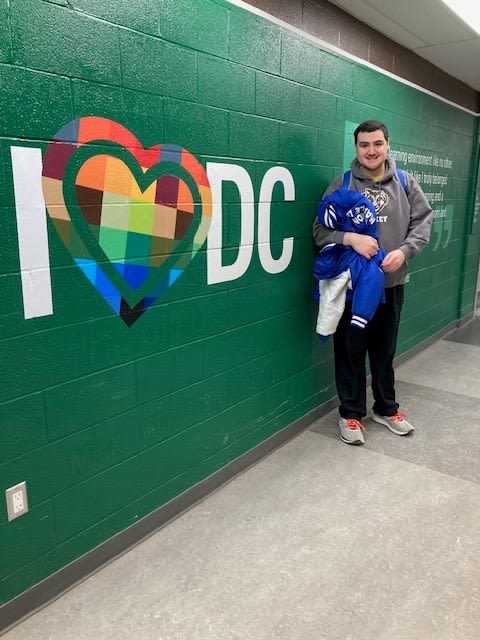 Joseph at Durham College standing beside DC sign