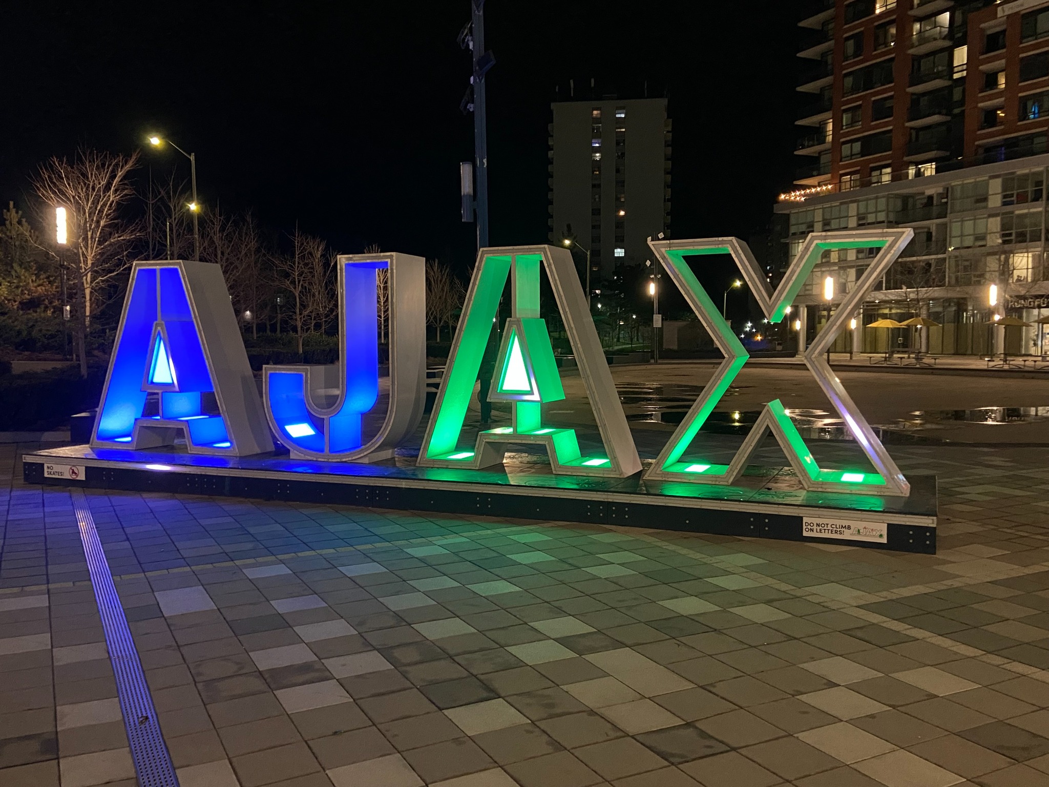 Town of Ajax sign in Bayly Square illuminated in blue and green for Community Living Month